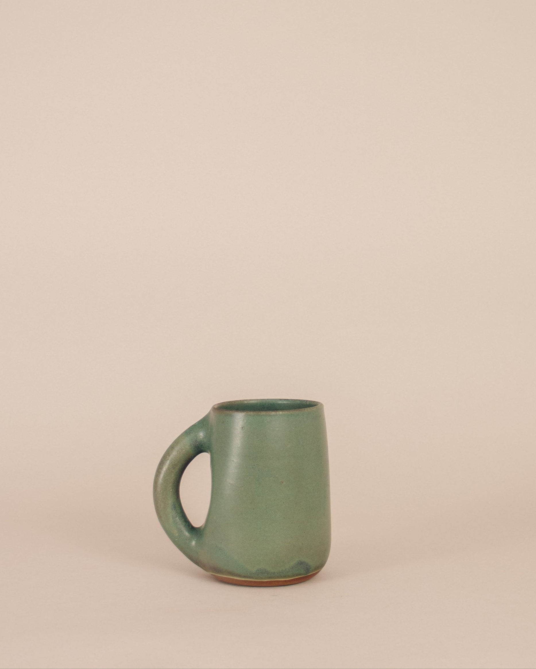 Green ceramic mug on a beige background