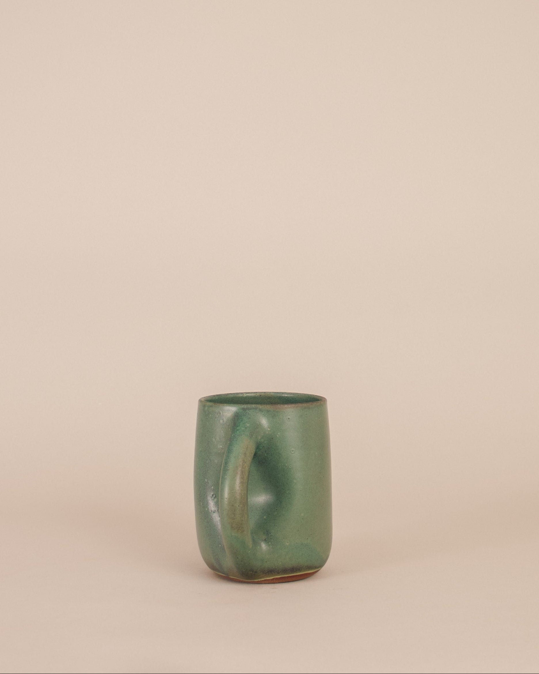 Green ceramic mug on a beige background