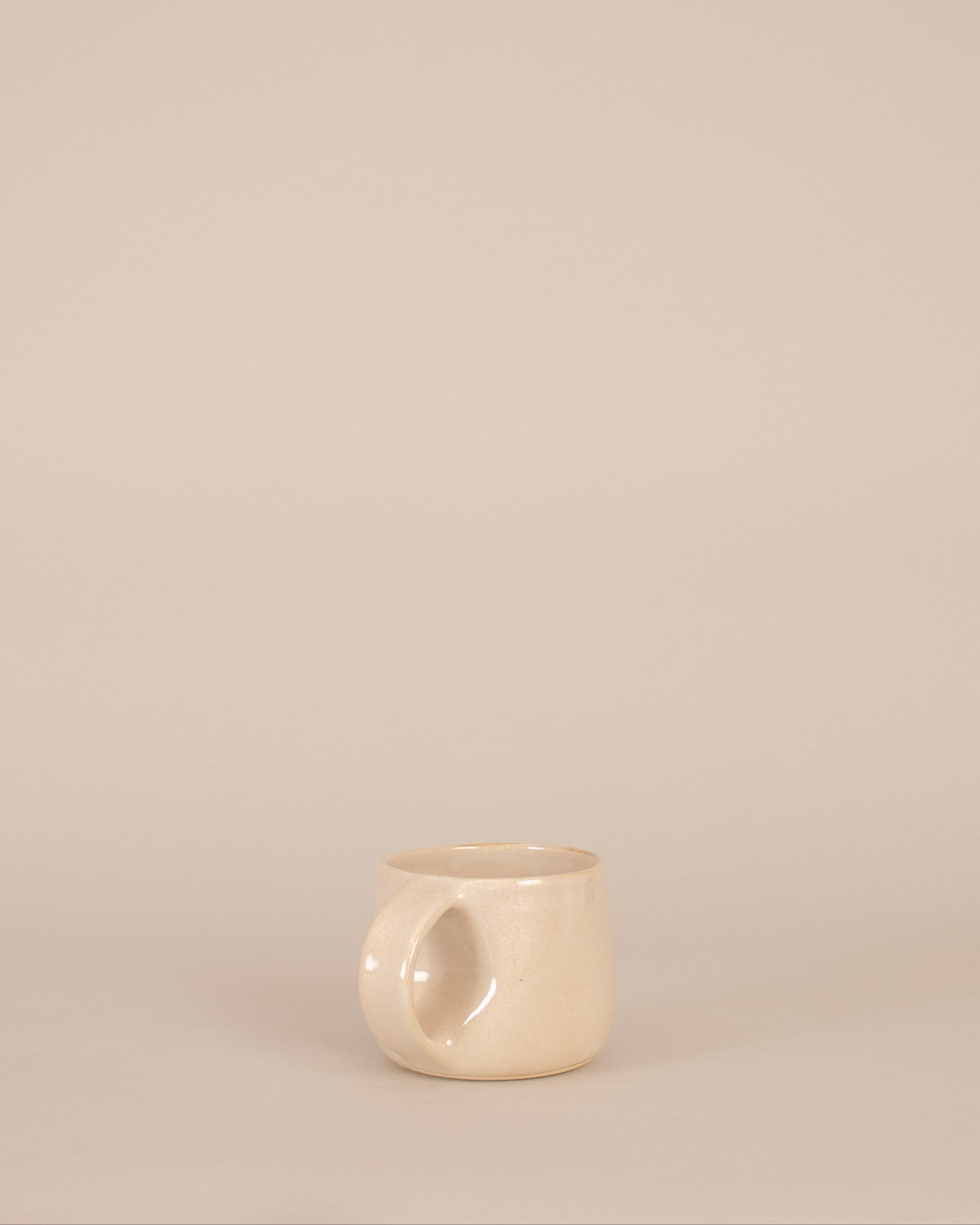 Small beige ceramic cup on a beige background