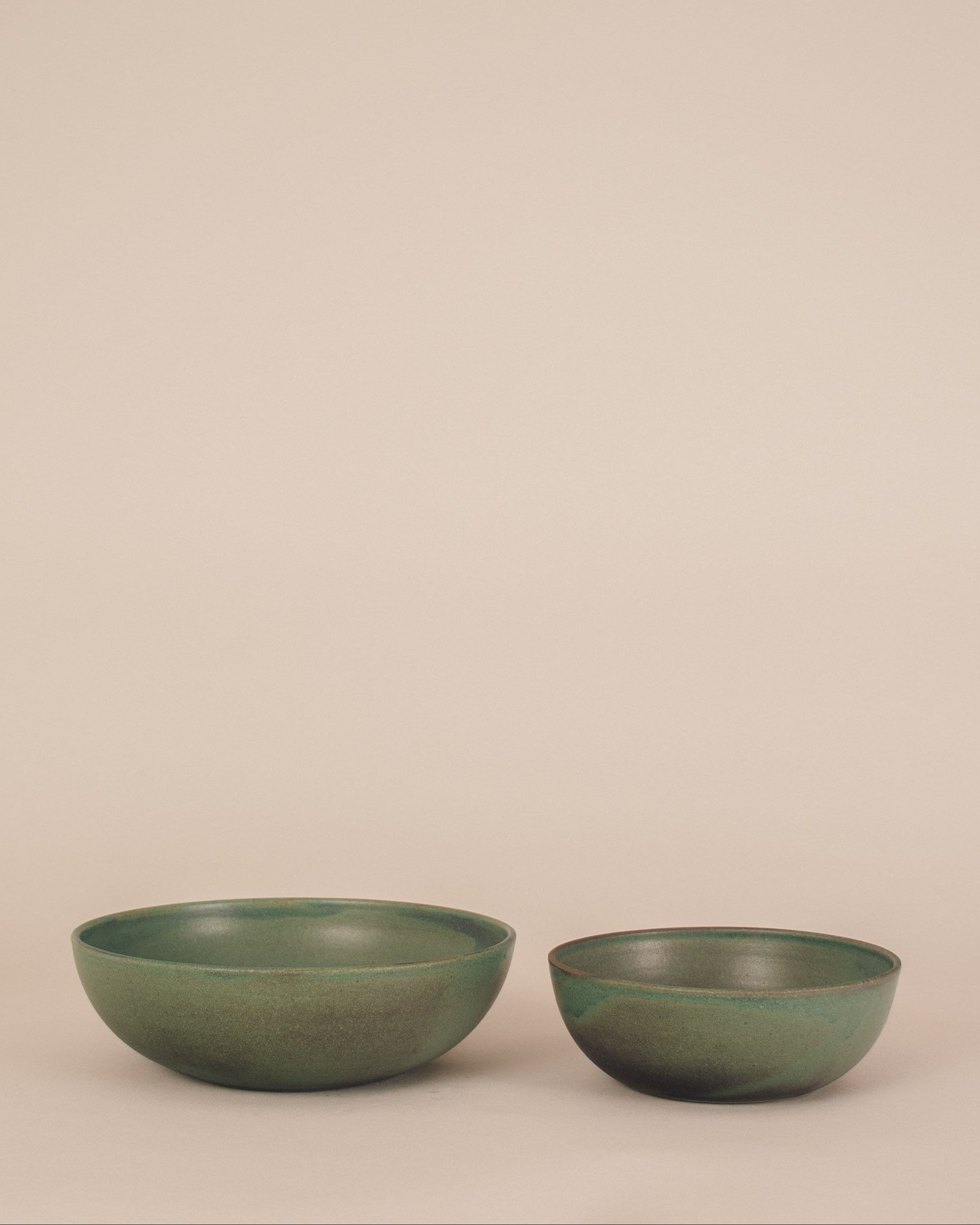 Two green ceramic bowls on a beige background