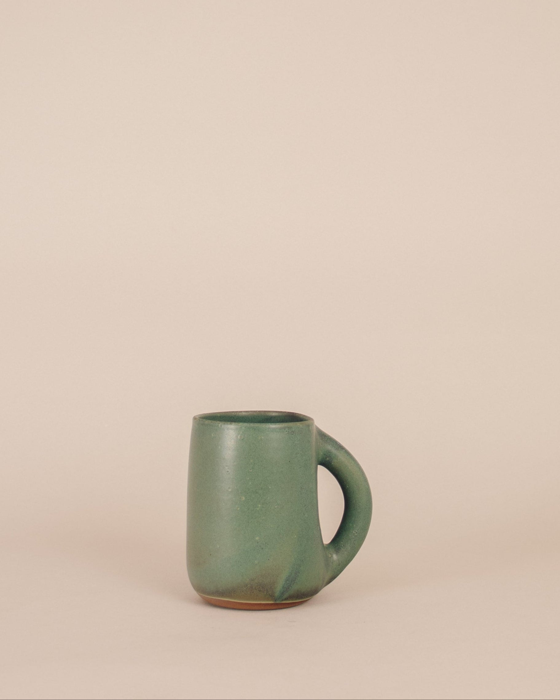 Green ceramic mug on a beige background